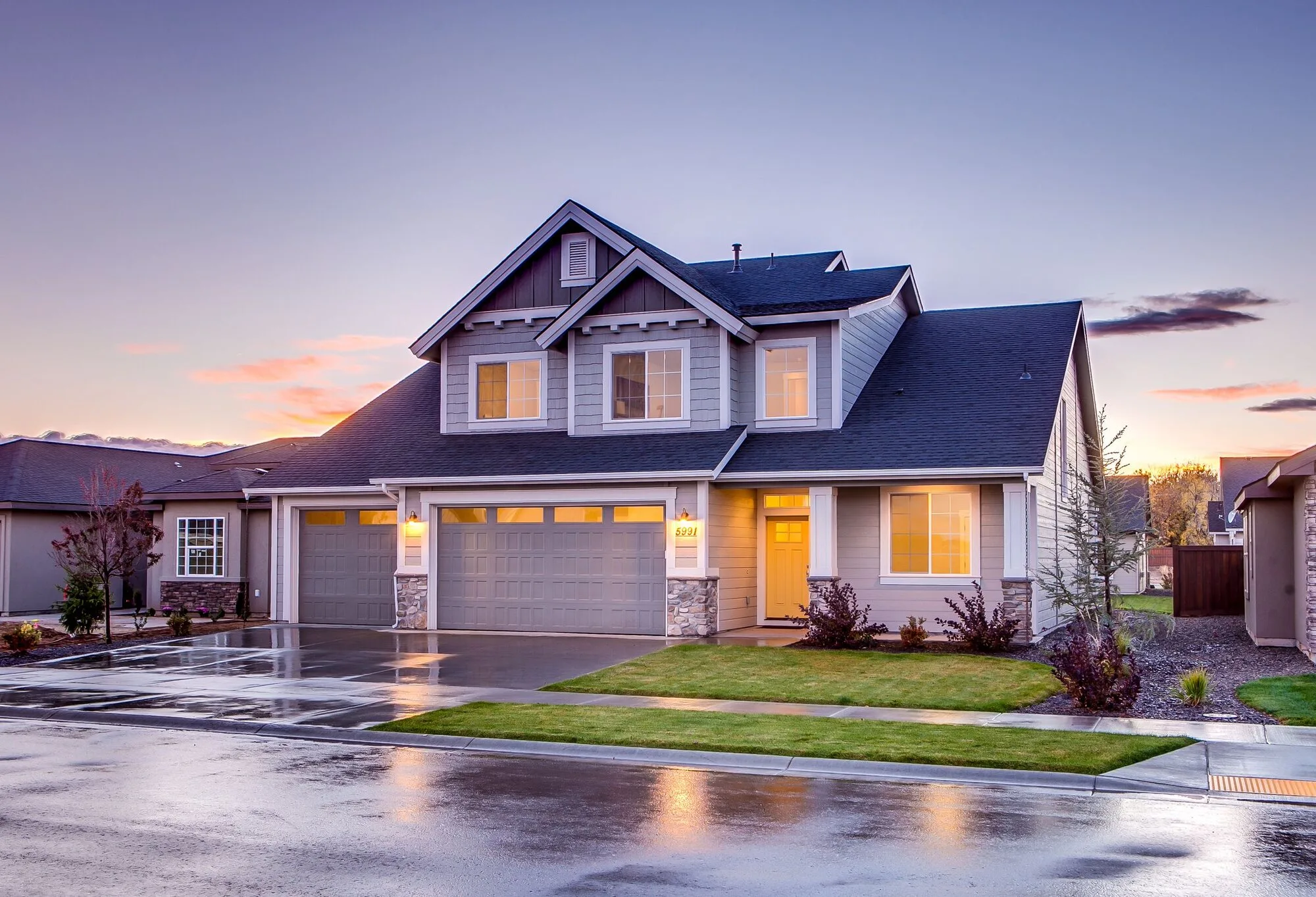 House exterior at dusk with a rain-wet driveway