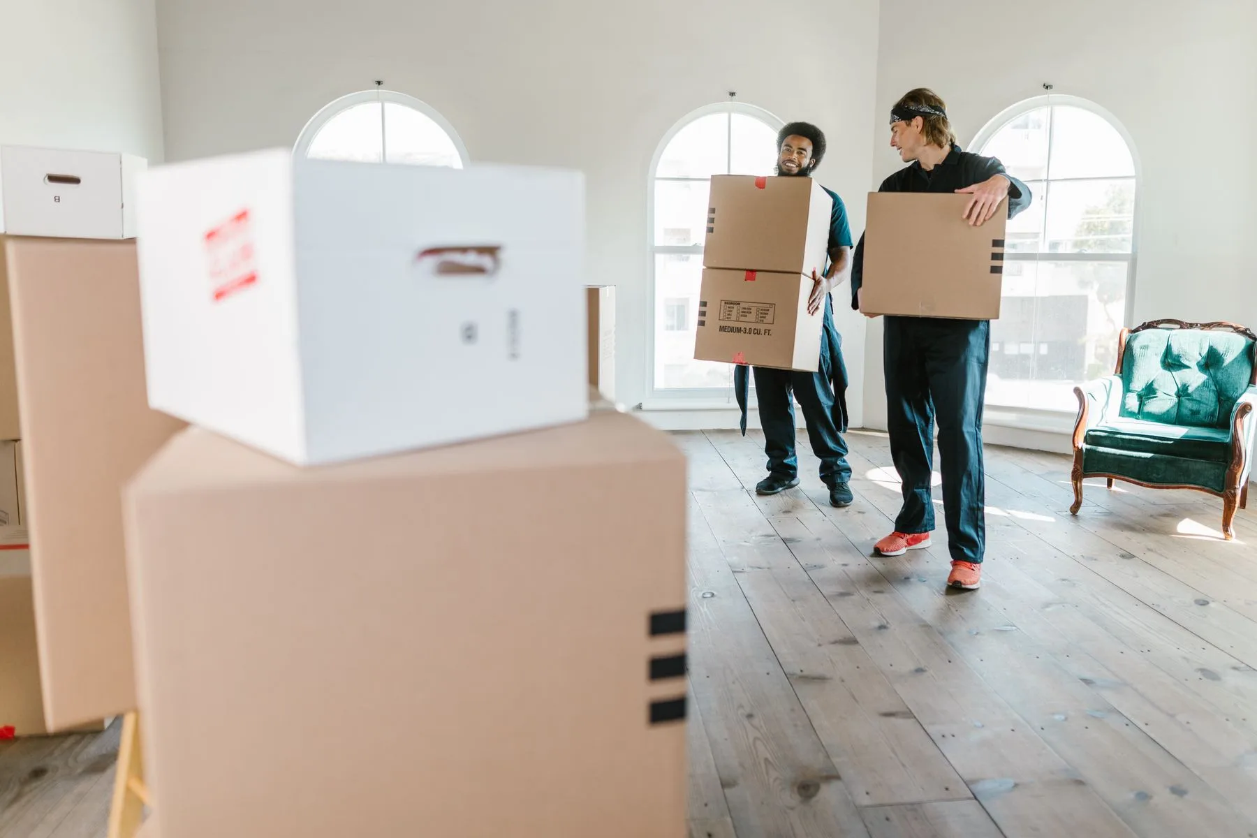 Stock photo of two people carrying moving boxes inside a home